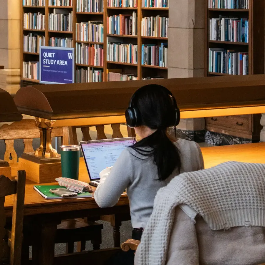 A student working on a laptop in a university library.