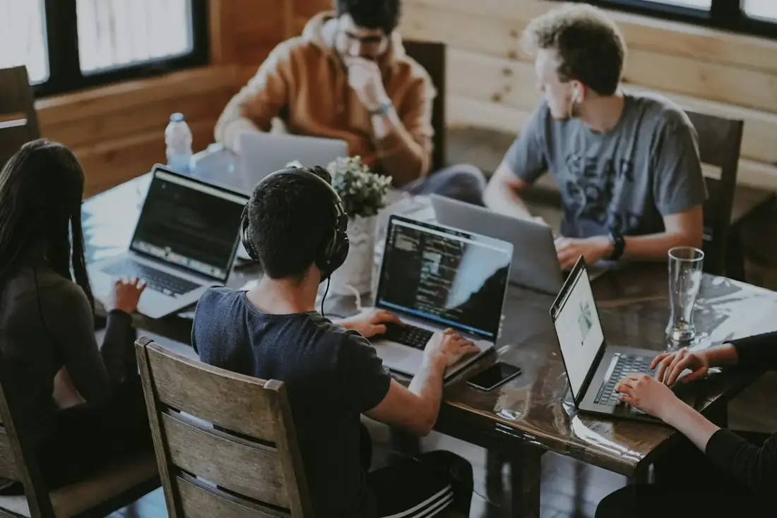 A small software team working on laptops around a shared table.
